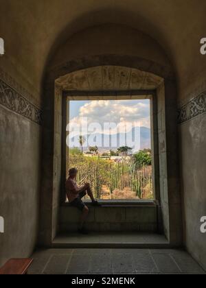 Uomo appoggiato nella finestra che si affaccia sul giardino del Museo delle Culture di Oaxaca, Santo Domingo, città di Oaxaca, Oaxaca, Messico Foto Stock