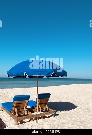 Sedie a sdraio e ombrellone in spiaggia Foto Stock