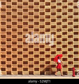 Ragazza con ombrello rosso oltrepassando il Padiglione polacco a Milano Expo 2015 Foto Stock