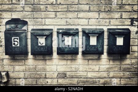 Metallo nero di cassette postali su un muro di mattoni Foto Stock