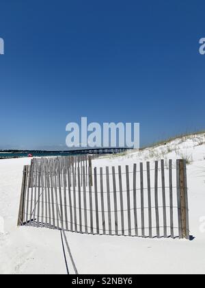 Seascape spiaggia con sabbia bianca, recinto, dune, acqua di smeraldo e il ponte con il blu del cielo Foto Stock