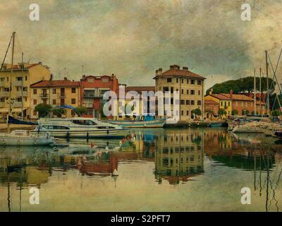 Gli edifici e le barche che riflette in grado canal - Grado Friuli Venezia Giulia, Italia Foto Stock
