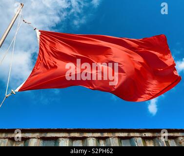 Bagnino di salvataggio red flag soffiando nel vento forte attenzione il nuoto è pericoloso Foto Stock