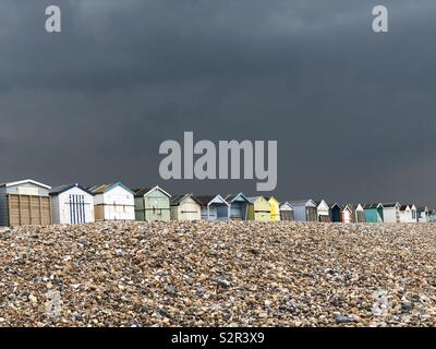 Un cielo scuro tempestoso su alcune capanne sulla costa a Lancing, West Sussex, Regno Unito. Foto Stock