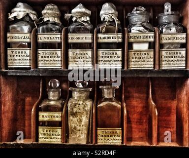 Antica medicina in bottiglie con tappi e etichette originali in armadio. Foto Stock
