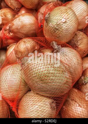 Fresche e mature le cipolle giallo in rosso net sacchetti. Foto Stock