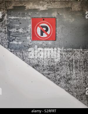 Alto contrasto immagine di colore rosso brillante nessun simbolo di parcheggio su terreni accidentati cemento parete esterna di parcheggio in garage. Foto Stock