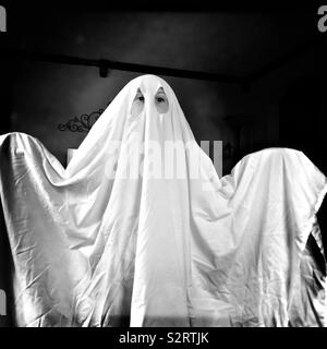 Un bambino che indossa un costume fantasma realizzato da un lenzuolo bianco. Foto Stock