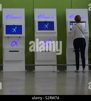 Viaggiatore femmina utilizzando automatico di check-in presso l'Aeroporto Internazionale di Atene Eleftherios Venizelos, a Spata, Attica, Grecia. Questo moderno aeroporto ha inaugurato il 28 marzo 2001. Foto Stock