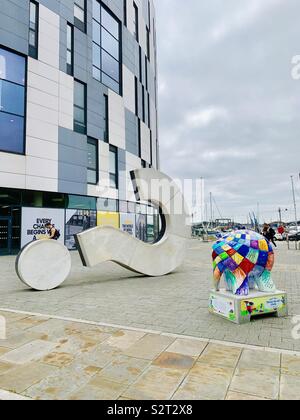 Ipswich, Regno Unito - 15 Luglio 2019: Università di Suffolk edificio del campus, un punto interrogativo e un sentiero Elmer elefante scultura. Foto Stock