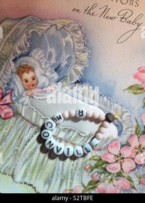 Vintage di perline braccialetto di riconoscimento per un neonato ragazza in un ospedale vivaio e un retro annuncio di nascita card, 1940s Foto Stock