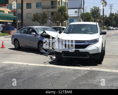 Due moderni veicoli coinvolti in un incidente di traffico sono mostrati in una città incrocio stradale durante il giorno. Foto Stock