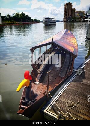 Un tradizionale malese Orang Ulu barca utilizzata per le crociere turistiche sul Fiume Sarawak Kuching Waterfront, Sarawak, Malesia, con una grafica stilizzata e intagliato di legno verniciato hornbill uccello come polena Foto Stock