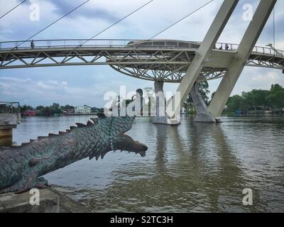 Uno di una coppia di cannoni disegnate come draghi cinesi che si affaccia sul Fiume Sarawak, con la Darul Hana ponte (Jambatan Darul Hana), Kuching Waterfront, Sarawak, Malaysia Foto Stock