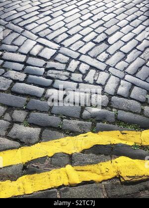 Strada di ciottoli con doppie linee di colore giallo Foto Stock