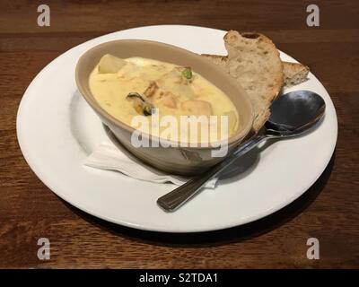 Cullen Skink tradizionale zuppa scozzese è mostrato, contenente il pesce bianco, patate, cipolle, latte e, in questa versione, le cozze. Il pane è servita sul lato. Foto Stock