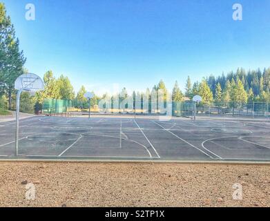 Campo da pallacanestro in una scuola tra la foresta durante le ore diurne Foto Stock