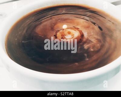 Goccia di latte in un moto vorticoso tazza di caffè Foto Stock