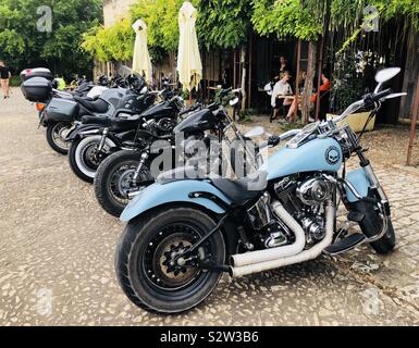 Fila di sedili f Harley Davidson Moto parcheggiate al di fuori di un ristorante in una cittadina francese Foto Stock