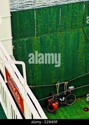 Bicicletta legata a funi accanto alla rampa di colore verde sul viaggio in traghetto Foto Stock