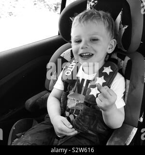 Bimbo di 2 anni in un sedile di vettura bloccata il suo dito medio. Foto Stock