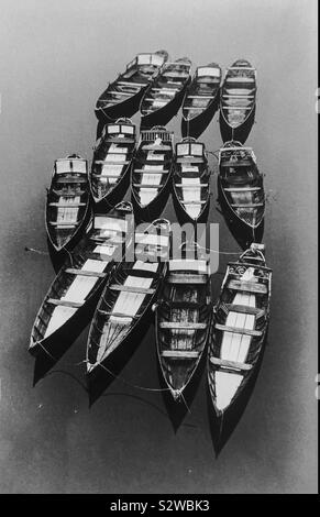 In legno barche a remi legati insieme in acqua ancora Foto Stock