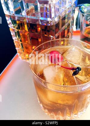 Close up di un Kentucky bourbon Manhattan sulle rocce di fronte al decanter di cristallo di Borbone, STATI UNITI D'AMERICA Foto Stock