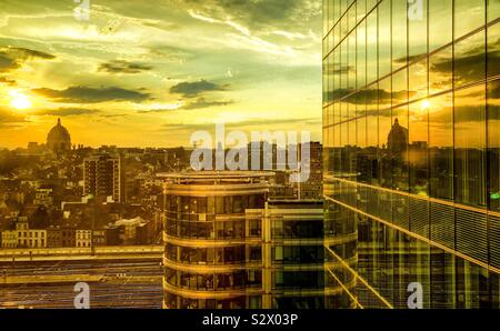 La mattina presto sorgere del sole in un modo significativamente e colorata sky, riflessa nel vetro di un edificio per uffici nel quartiere finanziario della città Foto Stock