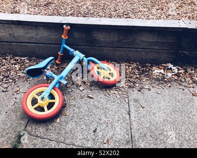 Un giovane bambino bicicletta formazione abbandonata sul pavimento. Foto Stock