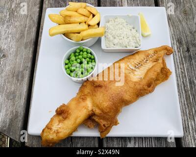 Tipico pesce e patatine con un lato di piselli freschi e salsa tartare Foto Stock