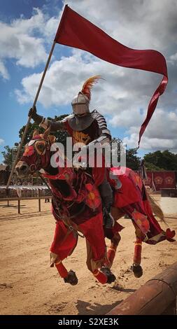 Il cavaliere rosso su un cavallo come parte della guerra dei Roses Visualizza presso il Castello di Warwick. Giostre. Cavaliere in Armatura scintillante Foto Stock