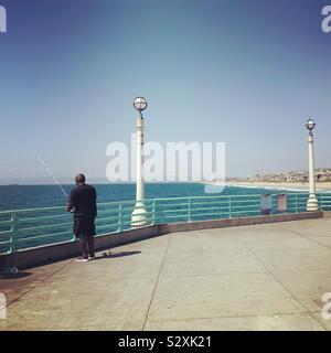 Un uomo pesca al largo di Manhattan Beach Pier, Manhattan Beach, California, Stati Uniti Foto Stock