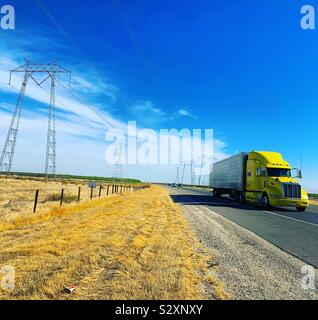 Un carrello con un taxi giallo passa dalle torri di trasmissione su un paesaggio piatto sotto cieli azzurri Foto Stock