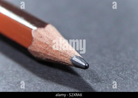 La punta di una matita in close-up su un fondo nero su un tavolo Foto Stock