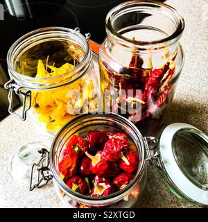 Rosso e giallo chilis essiccato in open Kilner jar storage su Corian cucina superficie di lavoro Foto Stock