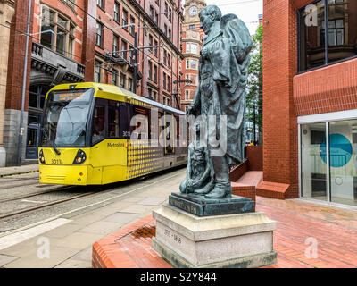 Tram Metrolink di Manchester passando Robert Owen statua Foto Stock