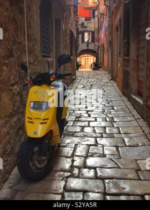 Un ciclomotore in un vicoletto nella splendida città vecchia di Rovigno, Croazia. Foto Stock