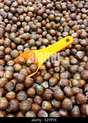 A bizzeffe di nocciole in un contenitore e un giallo-arancio scoop di dosaggio sul display in un negozio di strada Foto Stock