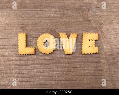 Amore parola composta con biscuit lettere su una tavola di legno Foto Stock