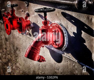 Rubinetti d'acqua dipinti di rosso a parete , Scozia, Regno Unito Foto Stock