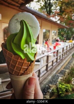 Tè verde Matcha gelato in una mano con due ragazza in tradizionali abiti kimono seduta sul patio. Fushimi Inari Taisha, Kyoto, Giappone. Foto Stock