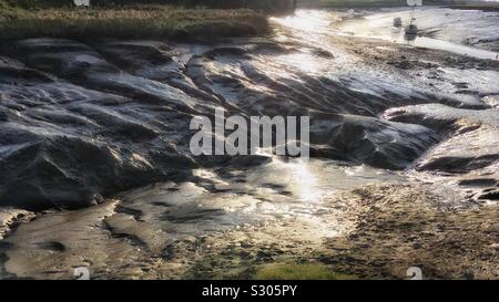 La bassa marea al creek. Spazzare mudbanks, la mattina presto luce su acqua bassa e distante barche. Foto Stock