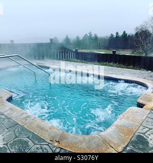 Vasca idromassaggio esterna che si affaccia sul paesaggio di montagna in un freddo giorno di novembre presso la Trapp Family Lodge, Stowe, Vermont, Stati Uniti Foto Stock