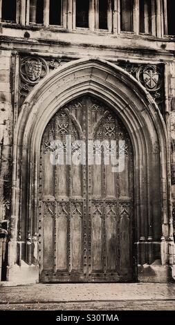 Porta in legno con arco scolpito sul lato esterno della cattedrale di Gloucester, Inghilterra Foto Stock