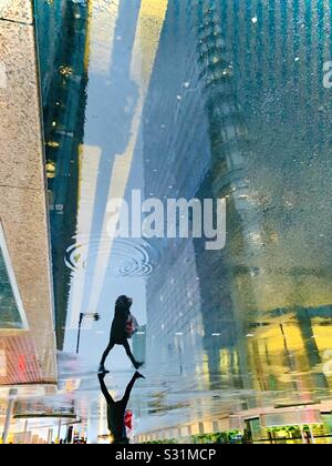 Silhouette di donna che cammina sotto la pioggia con doppie linee gialle Foto Stock