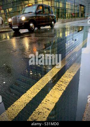 Cabina nera in una giornata di pioggia a Canary Wharf con linee gialle doppie Foto Stock