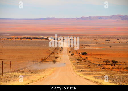 Vista prospettica guardando sopra un bel paesaggio come una vettura genera una nuvola di polvere su una strada sterrata. Foto Stock