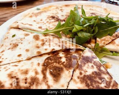 Pollo Quesadilla con foglie di rucola su piastra bianca Foto Stock