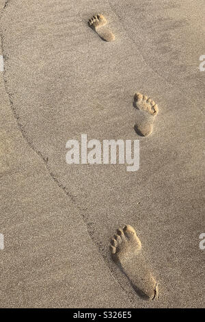 Impronte di piedi nella sabbia lungo la spiaggia. Foto Stock