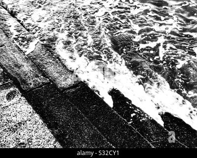 La marea che arriva lungo un volo di gradini Foto Stock
